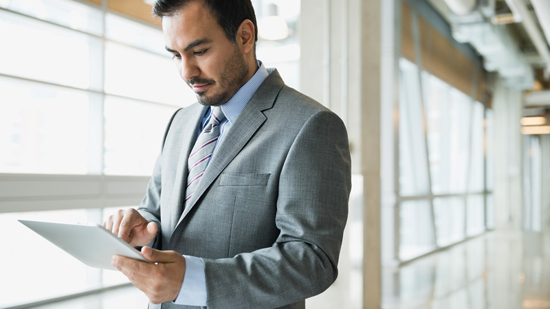 Man in a suit holding a tablet.