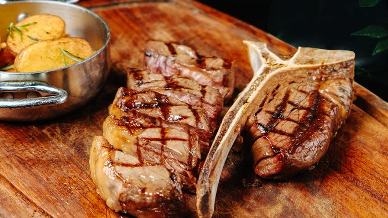 Grilled T-bone steak served with roasted potatoes.
