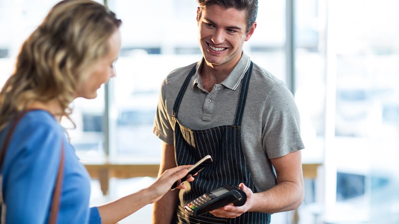 The man holding a pos terminal and the woman making a purchase with her smartphone