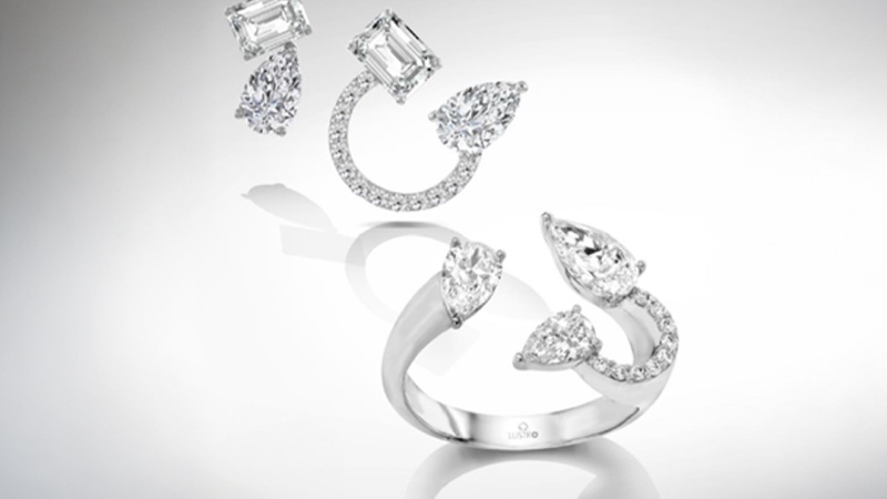 Two pairs of diamond earrings and a diamond ring with marquise and rectangular cuts on a reflective surface, arranged in an artistic layout.